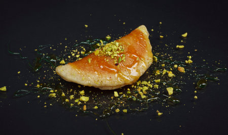 Qatayef, Traditional Arabic Ramadan Sweets with pistachio and honey on black background,side viewの写真素材