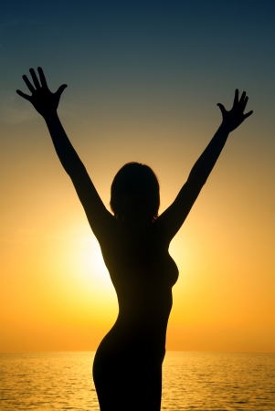 Happy woman silouette in the sunset on the beachの写真素材