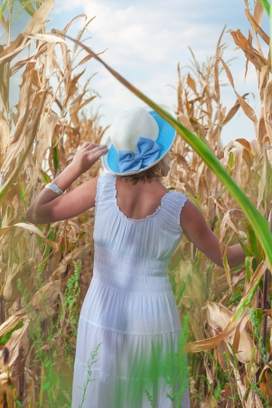 Young woman in the corn field with white dress from backの写真素材