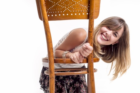 Young smiling woman behind a chair isolated on white backgroundの写真素材