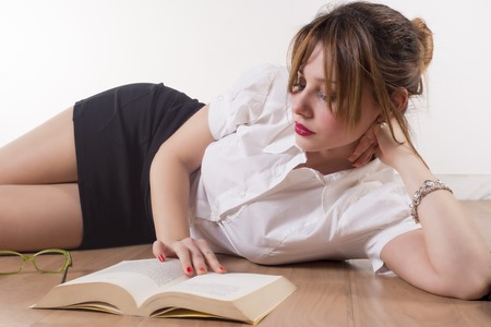 Sexy college girl reading a book on the floorの写真素材