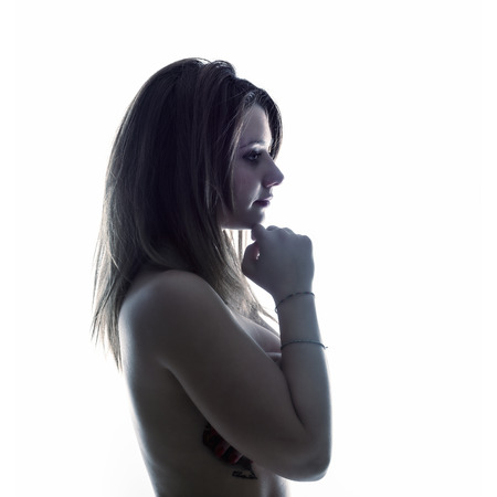 Isolated thinking woman in backlight on white backgroundの写真素材