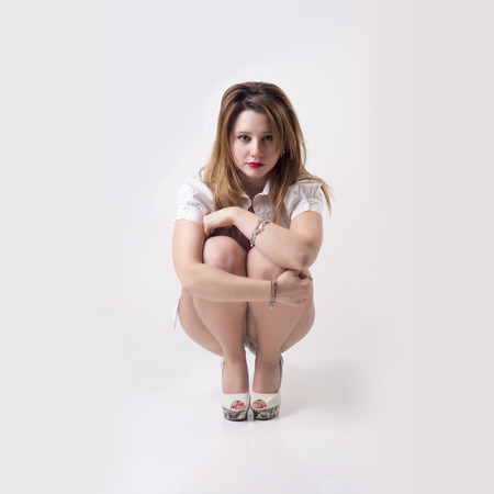 Isolated sad sexy woman sit alone in gray backgroundの写真素材