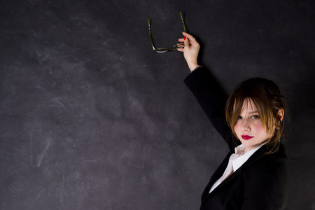 Sexy teacher looking you and pointing somthing on the blackboard with glassesの写真素材