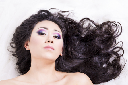 Front view of model portrait with black hair over white looking at youの写真素材