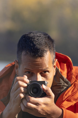 Portrait of traveler man at lake in autumn taking a photo with the digital camera