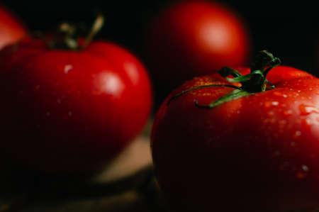 Close up of a lot of red big tomatoes on a black backgroundの写真素材