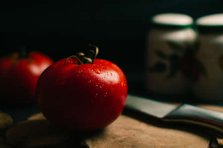 Red tomatoes on a black background, two steel knives and salts are lying nearbyの写真素材