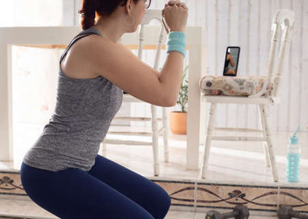 Woman practicing exercise with weights by video conference with the cell phone