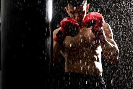 man training in the rain with a punching bag
