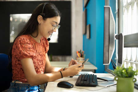 a young latina woman with long hair, using cell phone in the office
