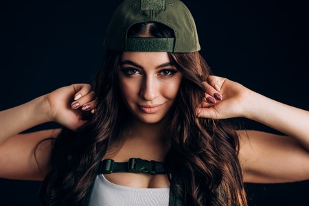 Sexy girl in military cap smiling and looking at the camera on a black backgroundの写真素材