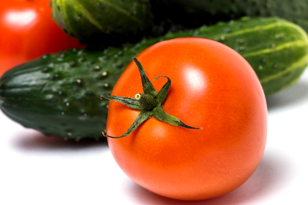 Fresh green cucumbers and red tomatoes on white background, closeup. Healthy diet, vegetarian food, summer vegetablesの写真素材