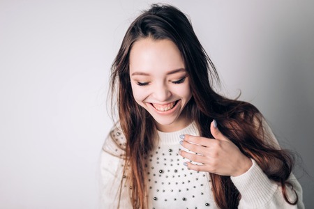 Beautiful woman laughing, smiling on a white background. Positive emotions, expressive facial features.の写真素材