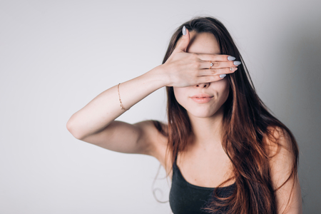 Young woman close her eyes with hand on white backgroundの写真素材