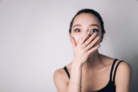 happy surprised woman covering her mouth on white background. Good news, happiness, gift, surprise.の写真素材