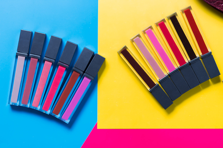 different shades of lipsticks, pink, red, maroon, light and dark blue, yellow background, top view, close upの写真素材