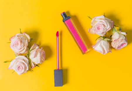 pink lipstick, lip gloss, open, with delicate pink shrub roses on the edges on a bright yellow backgroundの写真素材