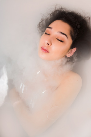Close-up portrait of a young woman, Pretty sexy brunette relaxing in hot tub with milkの写真素材
