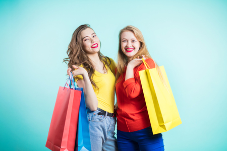 Beautiful girls with shopping bags are looking at camera and smiling while doing shopping. Positive emotions, joy.の写真素材