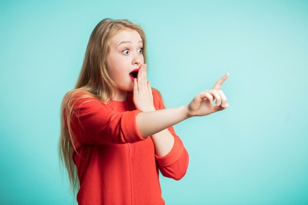 Woman happy and surprised shouts holds cheeks by hand. Beautiful girl pointing to looking right. Presenting your product. Expressive facial expressions, Emotionsの写真素材