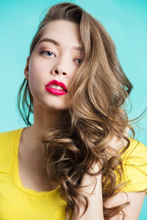 Close up portrait of a beautiful woman with professional makeup, red lips and long curls. Care, clean skinの写真素材