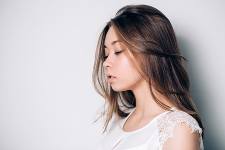 Sideways portrait of sad unhappy woman on a white background with copy space. Negative human emotions, face expressions.の写真素材