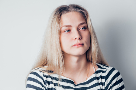 young beautiful sad woman serious and concerned looking aside and thoughtful facial expression, feeling depressed on white background. Negative emotions conceptの写真素材