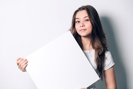 young smiling woman holding a blank sheet of paper for advertising, close-upの写真素材