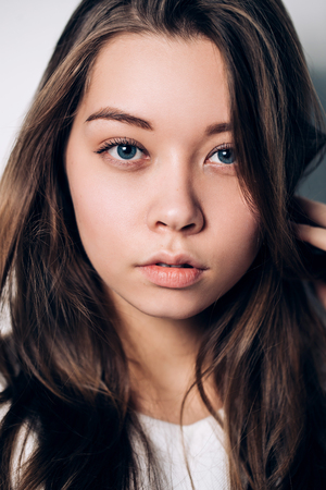 Portrait of beautiful blue eyed girl, close up, sad, serious gaze to the cameraの写真素材