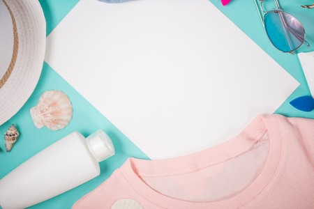 Flat lay of female holiday clothing and summer accessories. Pink t shirt, hat, sunblock, sunglasses...