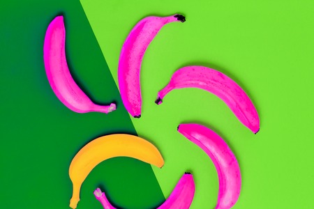 Flat lay of one yellow and pink bananas on colorful green background with copy space, top viewの写真素材
