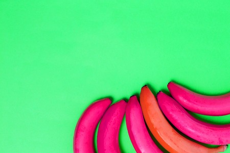 Colorful green background for text and advertising. pink and one red banana in the corner of the picture. From top viewの写真素材