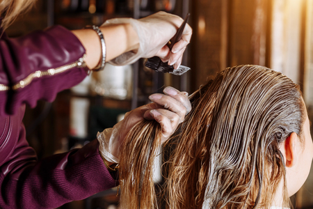 Young nice woman sitting in beauty hair salon happy smiling getting pleasure from the process of hair care. Close up. Hairstyle, spa, hair treatment concept.の写真素材