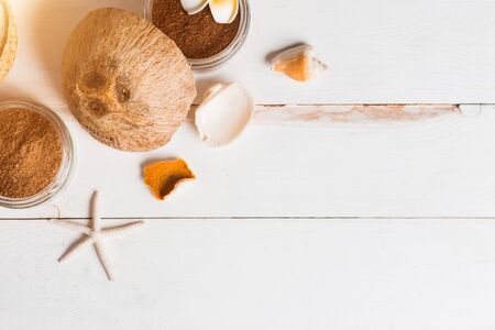 Homemade natural organic body and face scrub of ground coffee and coconut oil. Spa composition with beauty product, sea shells, orange peel, flower. Flat lay, top view, copy space.の写真素材
