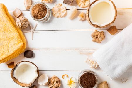 Frame made of coconuts, towels, spa beauty products, sea shells, decorations on white wooden background. Flat lay, top view, copy space. Travel, sea and relaxation.の写真素材