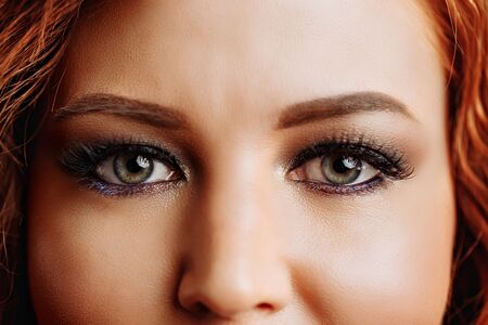 Close up portrait of young cute redhead woman with evening make up. Beautiful face of young woman with clean fresh skin close up. Color lenses, optics, ophthalmology, health concept. Good vision.の写真素材