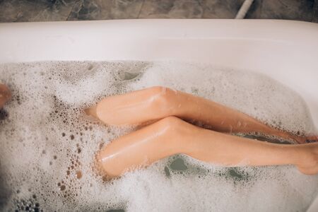 Gorgeous slim smooth beautiful legs, close up. Young woman having bath and showing her depilated...