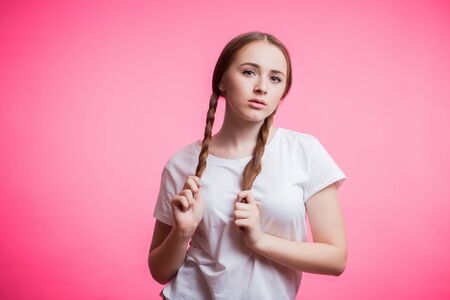 Young attractive girl holding for long braids. Portrait of beautiful smiling woman with beauty hair...