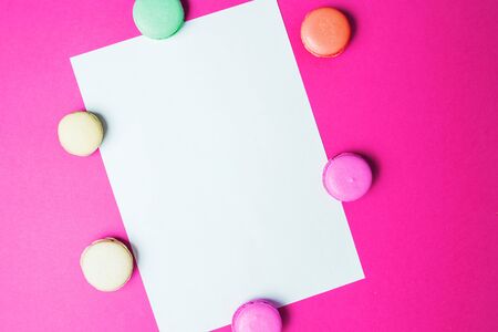 White paper frame on pink background with colorful macaroons. Flat lay, top viewの写真素材