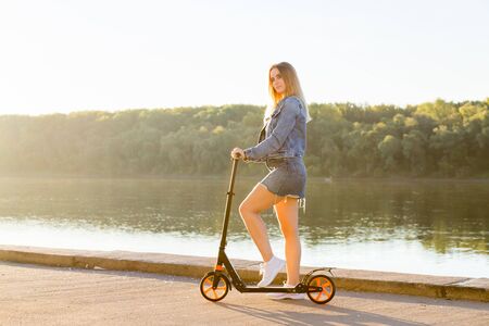 Full length portrait of a woman riding a scooter in nature