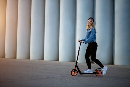 Happy young woman rides a scooter in the Park at sunset. Sports, walking, leisure, entertainment, Hobbies, summer conceptの写真素材