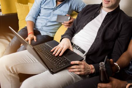 Cropped shot of three men colleagues working on laptop. Friends students sitting together on the...