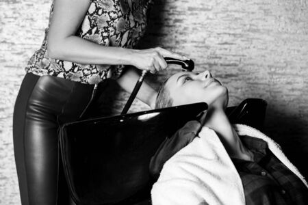 Closeup of a female hairdresser washing the hair the blonde girl. Spa, beauty, care, health concepts. black white photoの写真素材