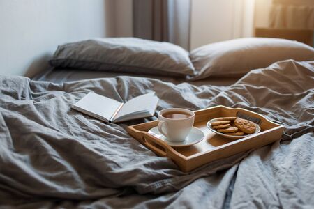 Breakfast of tea and biscuits with a Notepad and pen in a grey bed in the morningの写真素材