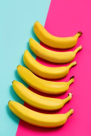 Beautiful row of yellow ripe bananas on colorful backgroundの写真素材