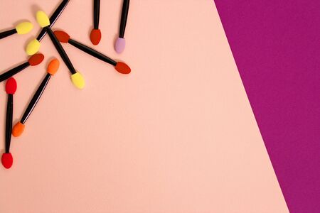 A bunch of applicators, eyeshadow brushes on a colorful bright background with copy space....