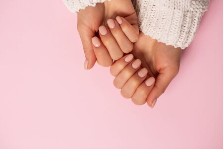 Closeup of beautiful hands, nails, delicate manicure on pink background. Care, beauty, Spa, salon concept, top view, copy spaceの写真素材