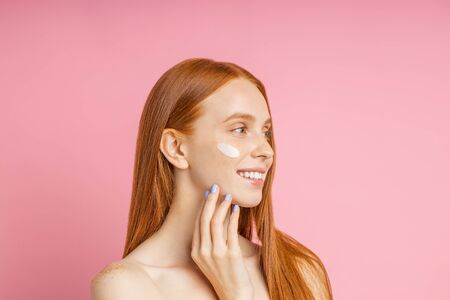 Beautiful young ginger woman with cream on face