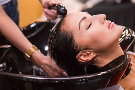Close up portrait of woman which wash hair in a beauty salon. Care and hair products conceptの写真素材